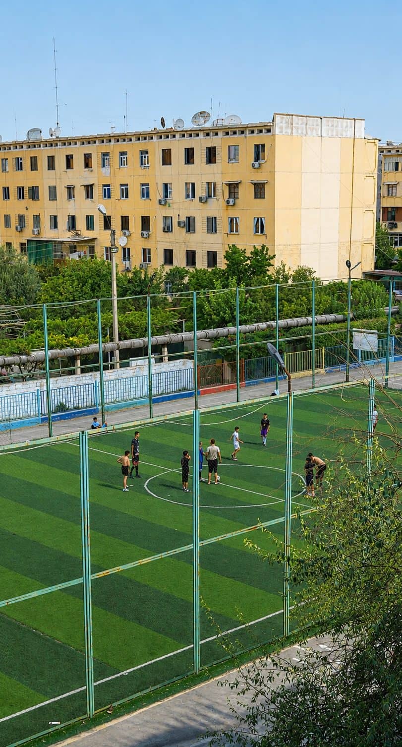 Maktab futbol maydoni — sun'iy qoplama va to'r bilan o'ralgan